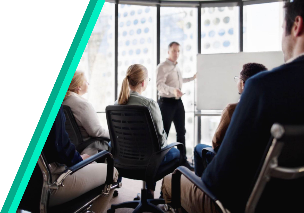 Large office with business professionals sitting in chairs and facing the presentor